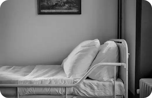 A black and white image of a neatly made hospital-style bed, representing Jango's support for participants transitioning from clinical settings back to the comfort of their own homes.