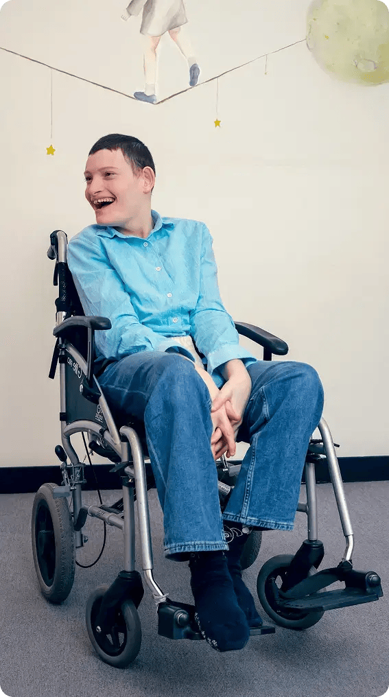 A smiling boy in a wheelchair, radiating joy and positivity.
