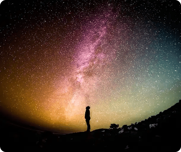 A silhouette of a person standing on a hilltop looking up at a vibrant, starry Milky Way galaxy, symbolizing the discovery of personal "Why" and the expansive future explored in the Pathways to Potential program.