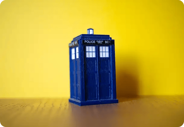 A miniature blue police box standing against a vibrant yellow background, symbolizing the transformative journey of discovery, adventure, and hope that NDIS participants experience through Jango’s respite and recovery services.