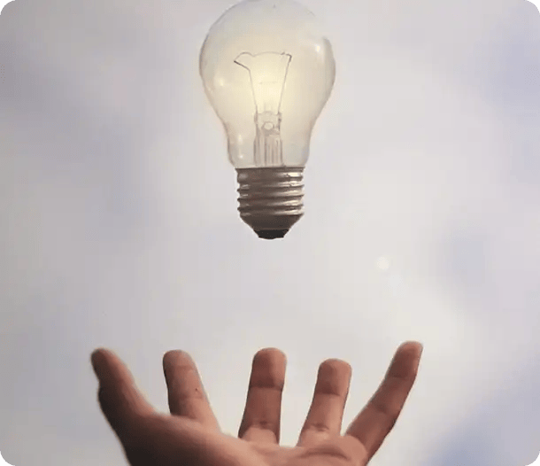 A glowing incandescent lightbulb floating just above an open palm against a bright sky, symbolizing the breakthrough ideas, expert insights, and innovative problem-solving Jango provides to help participants maximize their NDIS funding.