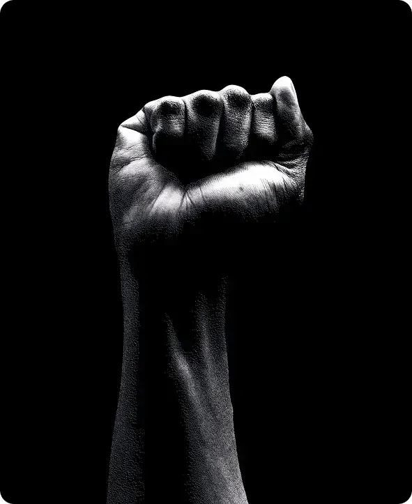 A striking black and white close-up of a raised clenched fist against a dark background, symbolizing the strength, advocacy, and empowerment Jango provides to NDIS participants on the Gold Coast.