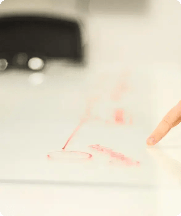 A finger points to a red circle on a blurred whiteboard plan, representing Jango’s collaborative and strategic approach to NDIS support coordination and individualized goal mapping for participants in Brisbane.