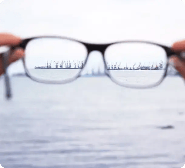 A pair of glasses held up to a horizon, bringing a blurry view of a harbor into sharp focus, symbolizing Jango’s role in providing clarity and direction for NDIS participants in Brisbane.