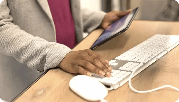 A close-up of a person in a professional grey blazer using a tablet and a white computer keyboard, representing Jango’s efficient digital systems for managing NDIS funding and providing remote support to participants across Northern NSW.