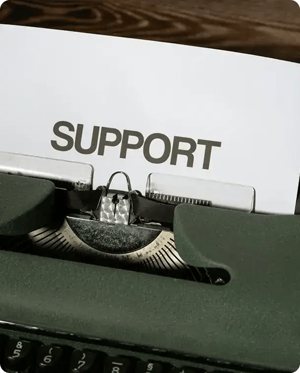 A close-up of a vintage typewriter with a sheet of paper that has the word "SUPPORT" typed in bold letters, representing Jango's dedicated approach to customized NDIS and aged care services.
