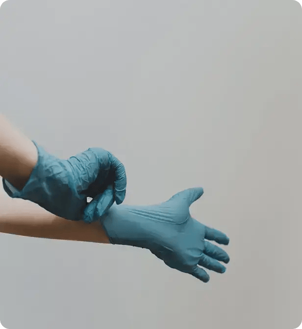 A close-up of a person putting on blue protective disposable gloves, representing the high safety standards and professional hygiene practices of Jango’s NDIS cleaning team.
