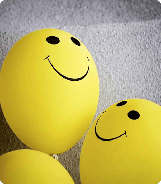 A close-up of bright yellow balloons with printed smiley faces, representing the positive reinforcement and improved quality of life outcomes achieved through Jango’s evidence-based behaviour support plans.