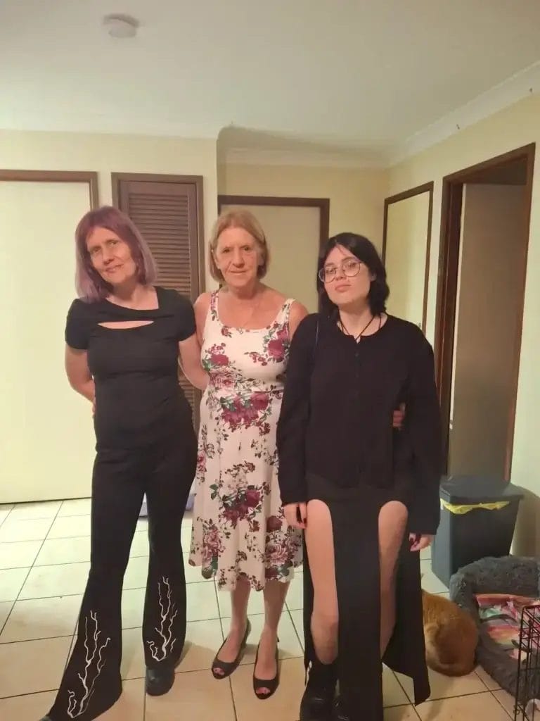Three women standing together indoors, smiling and posing for a photo as part of a featured success story, highlighting personal achievement and positive outcomes.