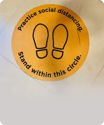 A close-up of a yellow floor decal featuring footprints and the text "Stand within this circle," used as a tangible parenting strategy to teach autistic children about personal space and social boundaries.